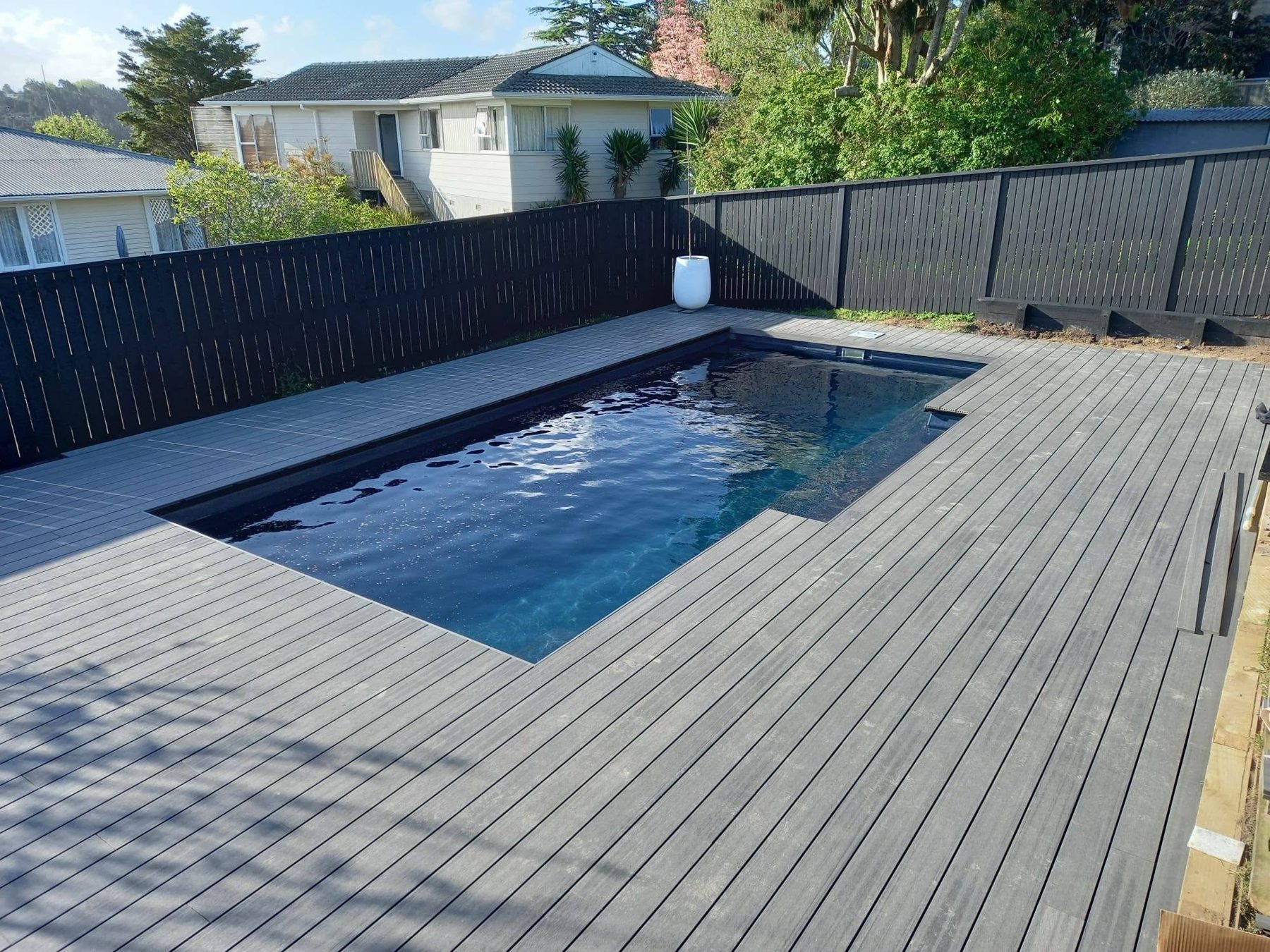 Composite decking laid around a rectangular lap pool with paving beyond