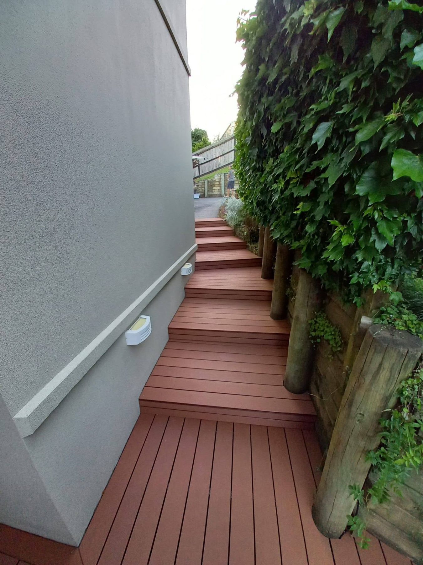 Composite steps climbing beside a planted wall
